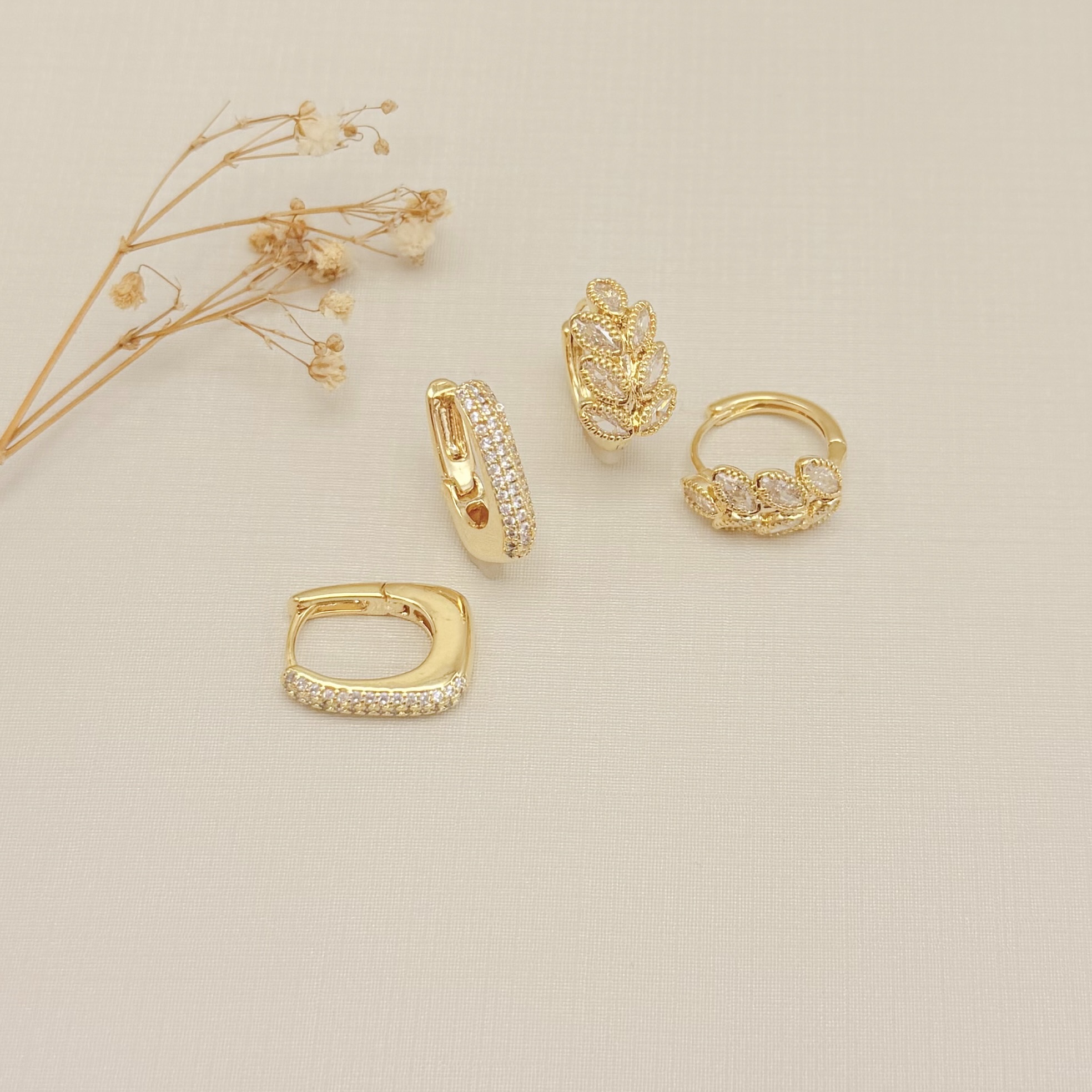 05.3107.1.O - Argola em formato retangular abaloado com três colunas de zircônias na frente.