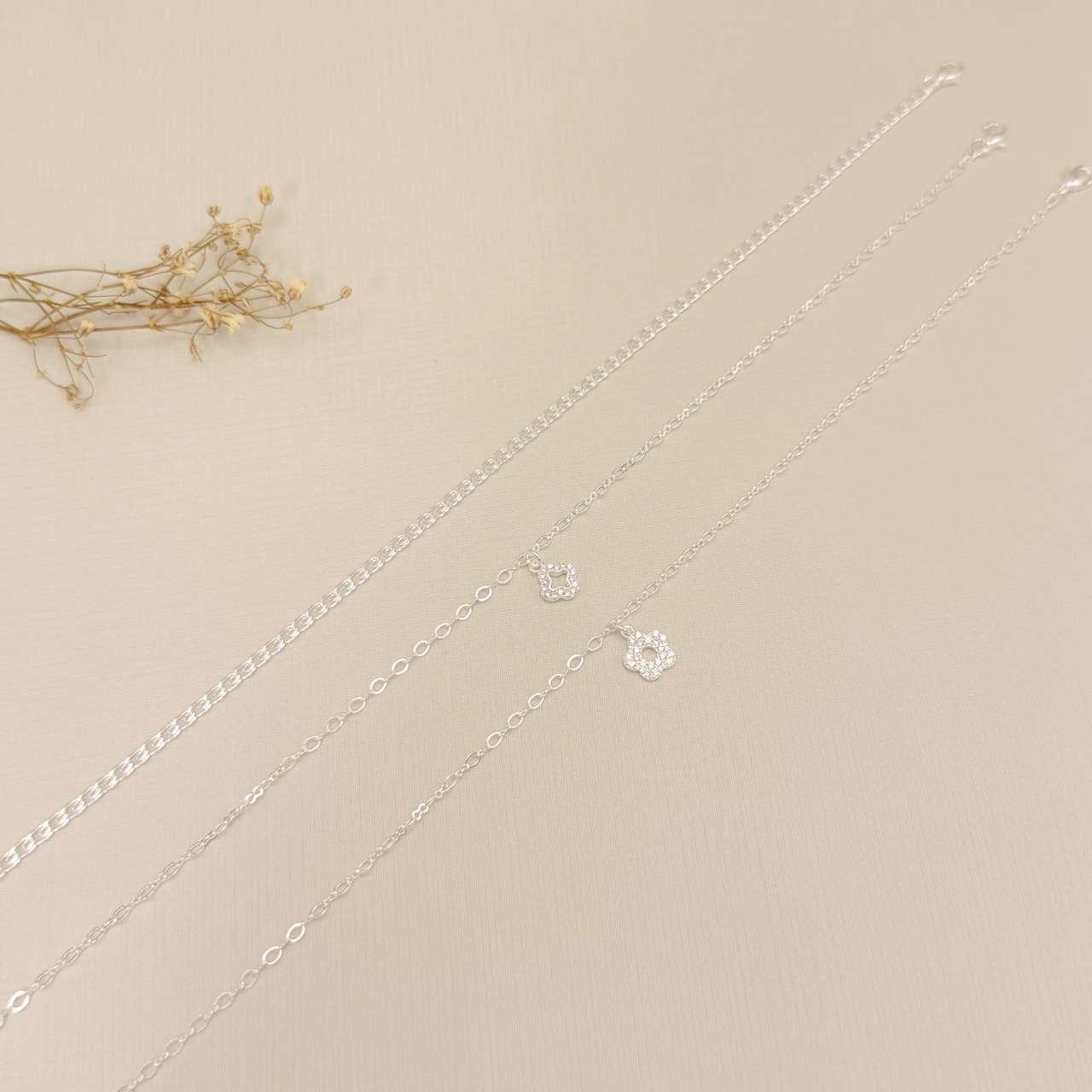 14.0335.1.S - Tornozeleira com pingente de flor cravejada e círculo vazado no centro, malha elo oval e elo infinito.