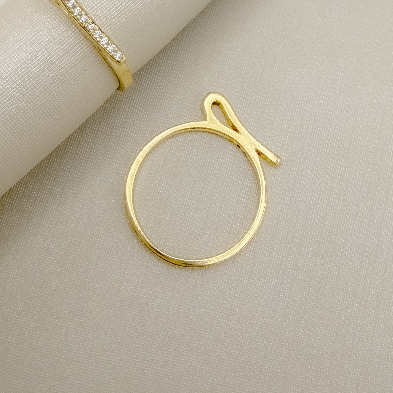 03.2562.1.O - (17) Anel de aro liso fino com central em efeito dobra alta cravejada