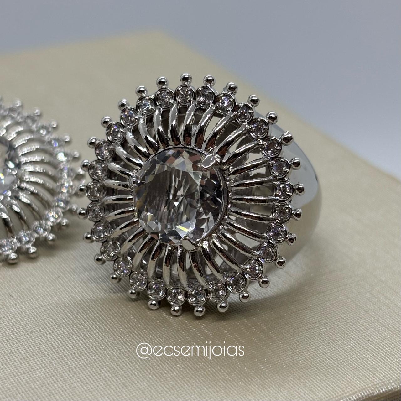 Conjunto de anel e brinco redondo com zircônia maior no centro, aro lateral vazado e borda cravejada - banhado a ródio branco