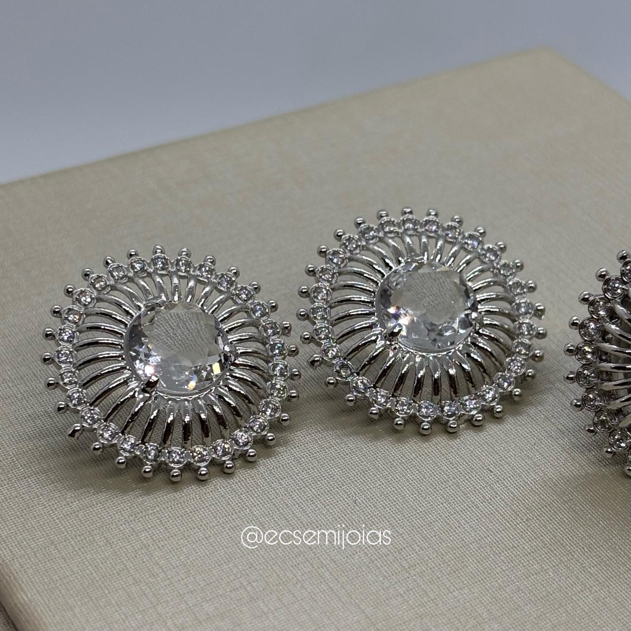 Conjunto de anel e brinco redondo com zircônia maior no centro, aro lateral vazado e borda cravejada - banhado a ródio branco